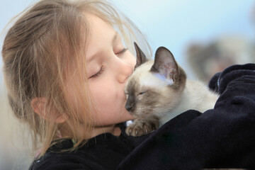 close up of little girl kissing a kitten 