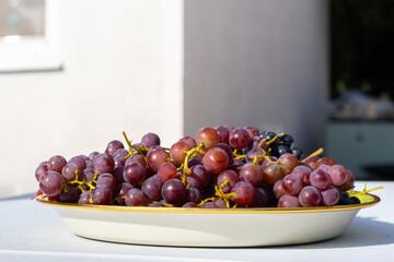 Grapes in a plate on a table outside on a sunny day
