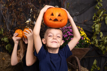 close-up portrait of happy, funny boy and a girl playing with pumpkin. children playing and...