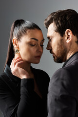 A loving couple in elegant attire stands confidently next to each other.