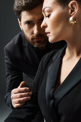 A stylish couple in elegant attire sitting closely together.