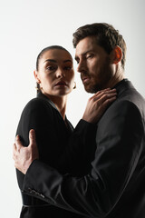 A man and a woman in elegant attire entwined in a loving embrace.