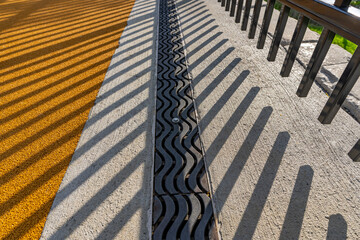 Late afternoon image of an ornamental metal trench drain in concrete with shadow pattern from an...