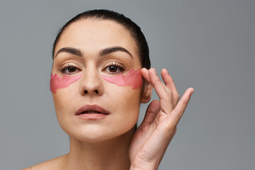 Alluring woman with pink eye patches enhancing her face.