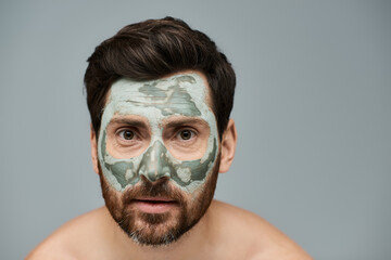 Alluring man wearing a facial mask, skincare.