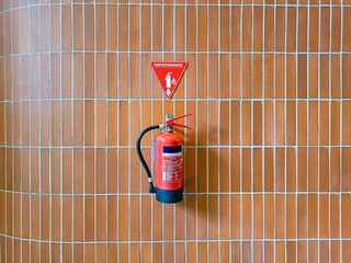 A red fire extinguisher hanging on the brick wall in the shopping mall