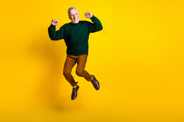Full size photo of nice senior man jumping winning dressed stylish green clothes isolated on yellow color background