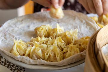 Hands skillfully wrapping delicate, golden dumplings - placed on a white cloth. Taken in Toronto,...