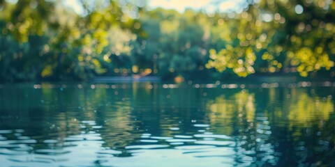 Fototapeta premium A peaceful lakeside view with bokeh reflections of trees on the water's surface.