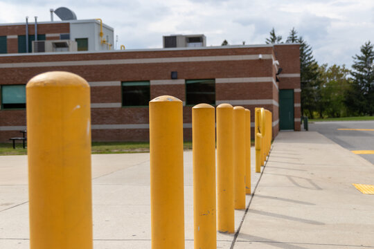 Yellow bollards lined up outside a brick building - industrial elements visible - under a partly cloudy sky. Taken in Toronto, Canada.