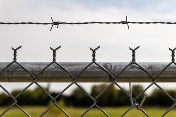 Barbed wire fence - clear sky backdrop - security boundary - restricted area - minimal cloud cover. Taken in Toronto, Canada.
