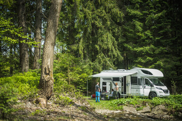 Couple Standing in Front of Parked Camper During RV Vacation