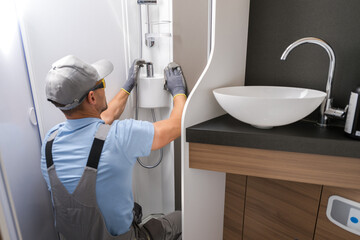 RV Industry Worker Cleaning Bathroom Faucet in Camper Van Bathroom