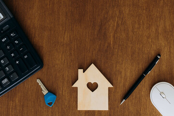 Wooden house, key and calculator on the table, top view, tax concept.