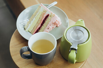 A piece of strawberry cake and tea on a wooden table in a cafe, close-up.