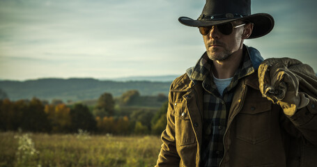 Man in Cowboy Hat and Jacket Walking Through Field