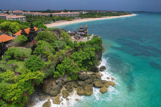 Aerial view of sandy beach with blue ocean waves, Pura Geger Dalem Pemutih indu temple, Pantai Nusa Dua, Bali, Indonesia.