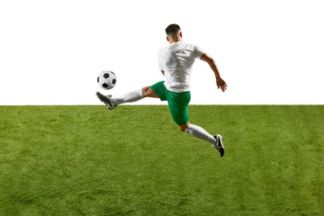Dynamic photo of young athlete man, soccer player training to kicking ball in mid-air on green field against white studio background. Concept of professionals sport, competition, tournament, action.