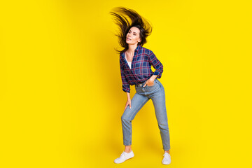 Full length photo of lovely young lady dance fluttering hair dressed stylish plaid garment isolated on yellow color background