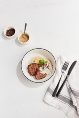 Beef Medallions with Creamy Sauce and Mashed Potatoes on White Plate