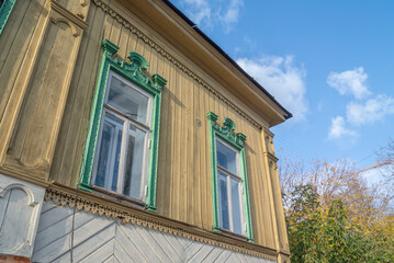 Windows with carved wooden frames of an old log house, sheathed in boards. An old wooden house and...