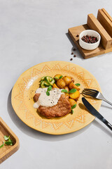 Delicious Pork Chop with Potato Wedges and Creamy Sauce on Decorative Plate