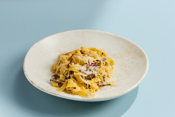 Creamy Mushroom Pasta on Light Blue Background with Parmesan Cheese Garnish