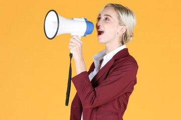 Portrait of young business woman shouting on the megaphone over yellow  background
