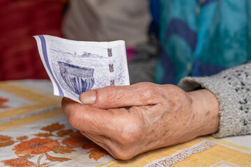 Elderly woman clutches a 50 Danish kroner banknote in her hand, Concept, Denmark finances of...