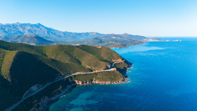Aerial drone view of a road leading along the North coast of Corsica island, France.