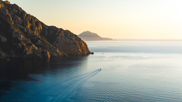 Aerial drone view of speed boat floating in front of the coast of Corsica during sunset, France.