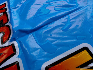 water splashes on the smooth and shiny surface of the flex banner. The tarpaulin material is...