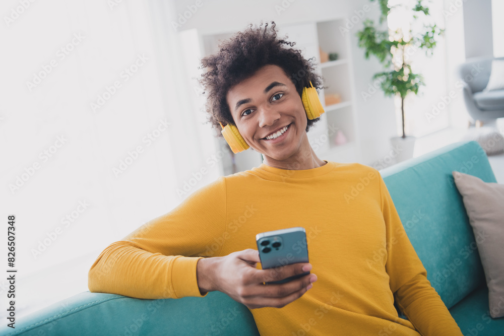 Sticker portrait of nice young man headphones smart phone wear yellow pullover white interior flat indoors