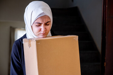 Arabic muslim woman holding carton boxes in her hand