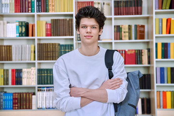 Portrait of college student guy with crossed arms inside library of educational building