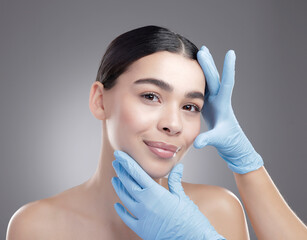 Doctor hands, woman and plastic surgery for cosmetics, aesthetic and facial transformation in studio. Medical surgeon with young patient in portrait for facelift, filler or beauty on gray background