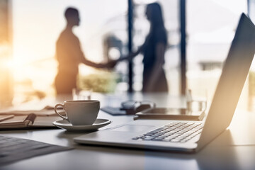 Handshake, laptop and business people silhouette with lens flare, crm and thank you with greeting and welcome of staff. Tech, cup and desk at a company in the morning at meeting with computer and b2b