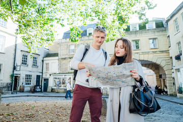 Fun, friends, travel and tourism concept. Young couple looking for direction during travel walk in old European city. Tourists consulting with a city guide map . Explore a new city together