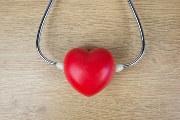 Stethoscope and red heart on a wooden table.