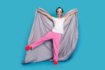 Full size photo of nice young woman hold blanket wear pajama isolated on blue color background