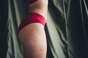 Cropped unretouched photo of girl in red panties stand profile side isolate dgren color linen...