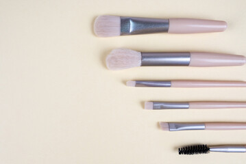 Makeup brushes on a beige background with copy space.