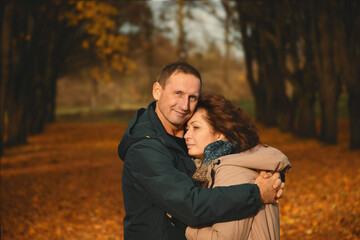 a married couple over 50 years old walks in the park in autumn and hugs