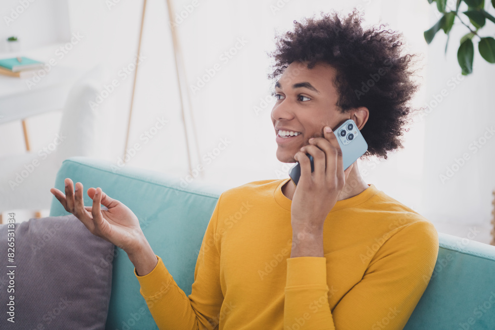 Sticker Portrait of nice young man speak telephone sit sofa wear yellow pullover white interior flat indoors