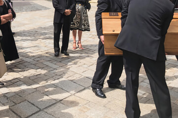 Men of funeral service loading the coffin into the hearse