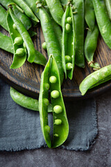 Fresh green peas on the table in a grey pot on dark background 