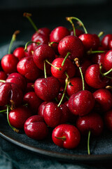 Fresh red cherries on the plate on dark background 