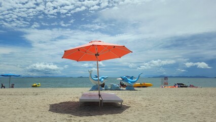 Beautiful tropical scenery, two sun beds and orange umbrella. White sand, blue sky clouds at Mui Nai beach, Ha Tien, Vietnam in summer.