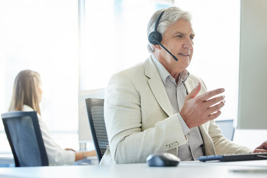 Mature man, talking and call center with headset for customer support, communication or service. Contact us, CRM and consulting agent at desk for student aid, career guidance or scholarship advice