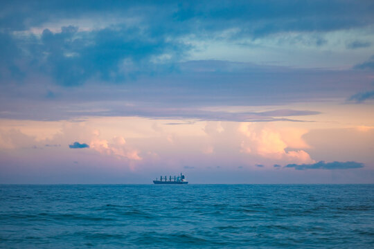 Cargo ship lined up at sea en route to Newcastle Harbour under a vibrant sunset sky